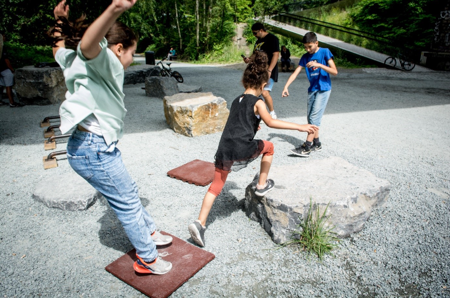 Des enfants pratiquent un parkour, parcours d’obstacles naturels, dans un parc. 