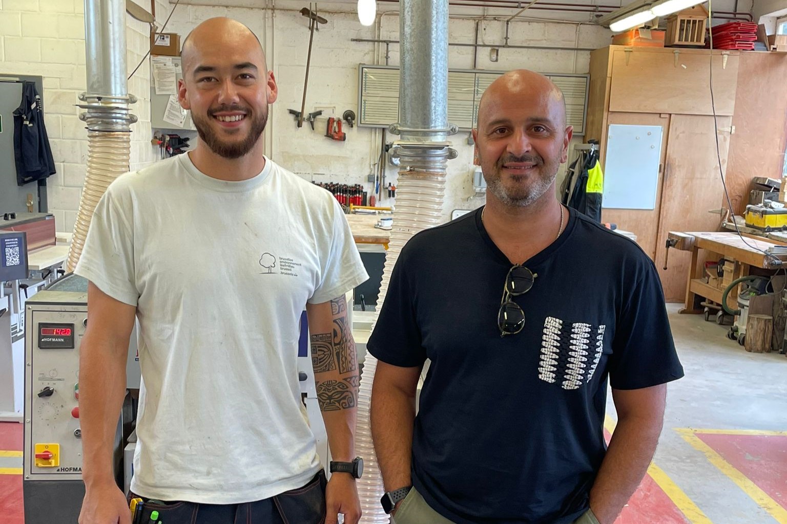 Sacha et Mehdi posent pour la photo dans l'atelier de menuiserie de Bruxelles Environnement.