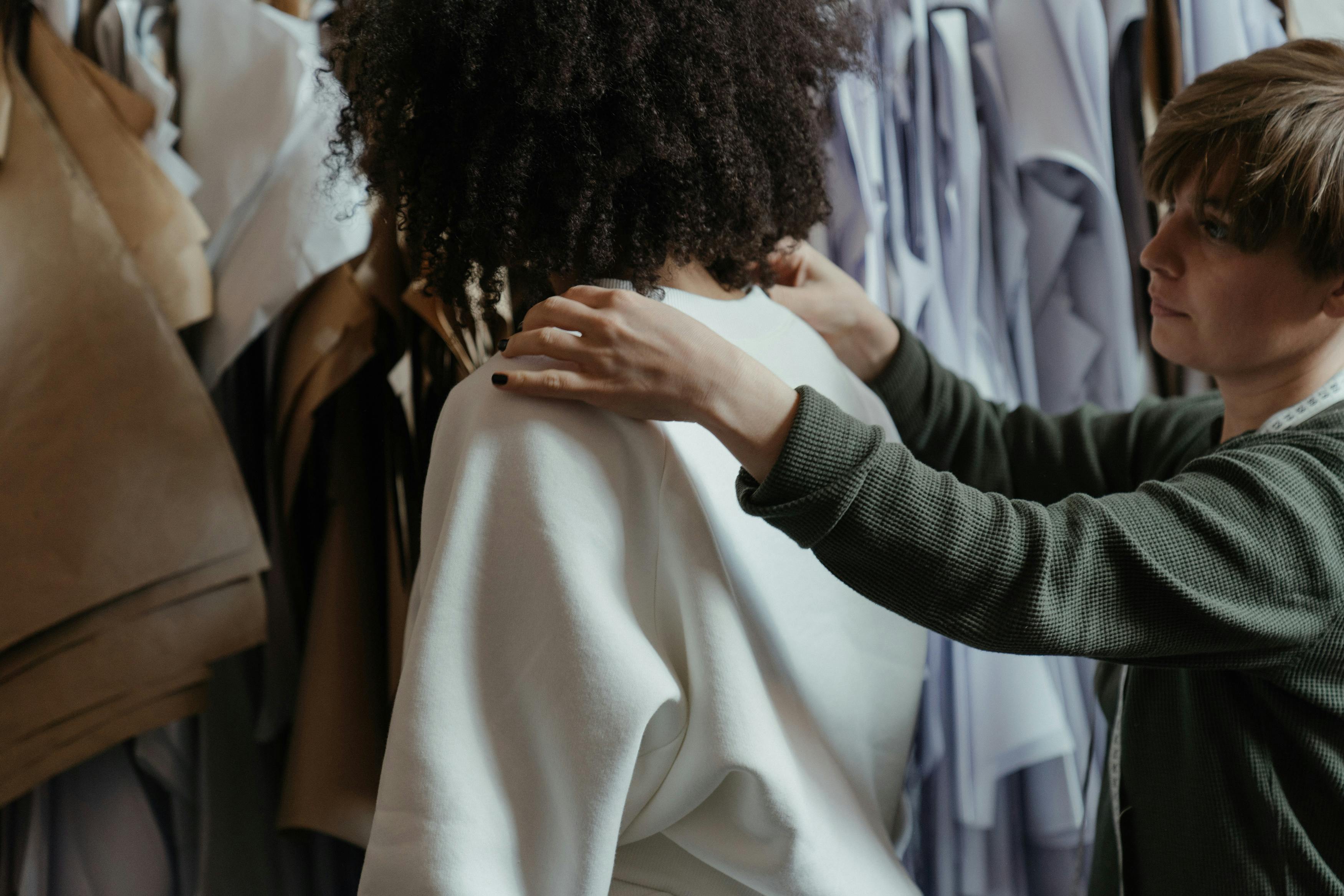 Une femme de dos avec une couturière qui prend une mesure