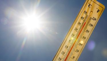 Thermomètre indiquant 30°C avec le soleil en fond