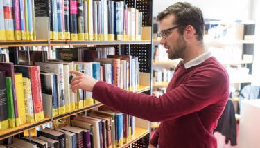 Homme dans une bibliothèque publique qui consulte des livres