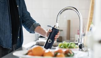 Personne qui rempli sa gourde au robinet